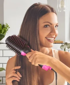Žena sa osmehom pokazuje svoju sjajnu i voluminoznu frizuru napravljenu fen četkom