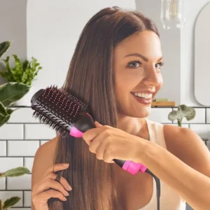 Žena sa osmehom pokazuje svoju sjajnu i voluminoznu frizuru napravljenu fen četkom